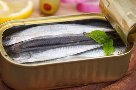 An opened can of sardines or herring in olive oil on wooden table. Healthy sea food full of omega 3 fats.
の写真素材
