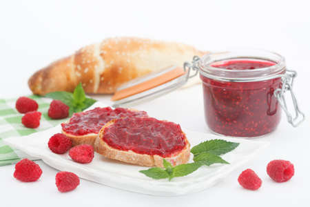 Raspberry jam with fresh raspberries and bread slices on white background. Homemade marmalade,...