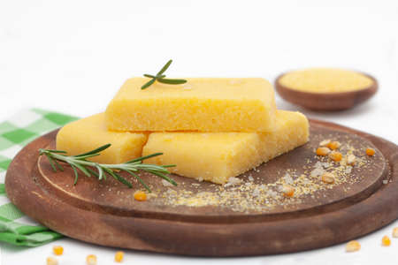 Corn polenta slices with grinded corn on wooden board. Homemade palenta, healthy vegetarian food.の写真素材