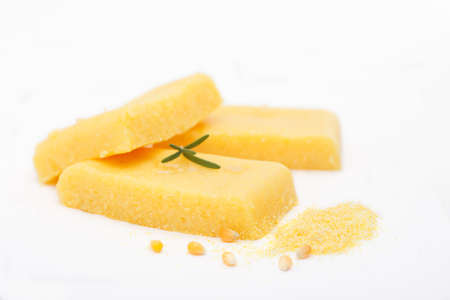 Corn polenta slices on white background. Homemade palenta, healthy vegetarian food.の写真素材