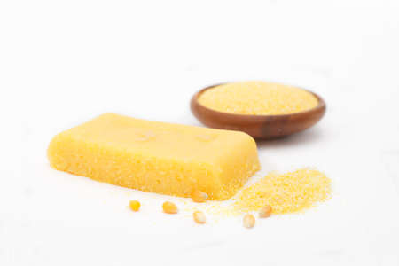Corn polenta slice with grinded corn in a bowl on white background. Homemade palenta, healthy...