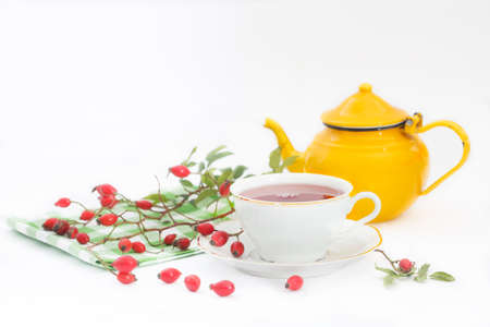 Cup of rose hip herbal tea with rose-hip fruits and pot on white background. Dog rose autumn or winter healthy tea. Strengthening the immune systemの写真素材
