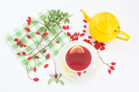 Cup of rose hip herbal tea with rose-hip fruits and lemon on white background. Dog rose autumn or winter healthy tea for strong immune system. Top viewの写真素材
