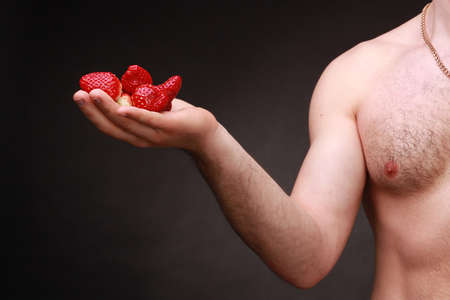 A handful of fresh red strawberry berries on a mans handの写真素材