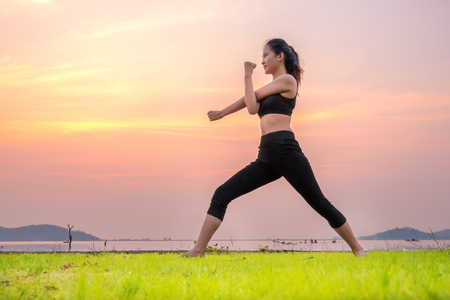 Yoga woman is relax with beautiful sunset background on the fresh grass as floor.の写真素材