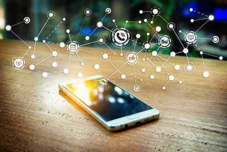 Smartphone on the wooden bar in the coffee shop. And communication icon network.の写真素材