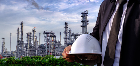 The engineer is holding a safety helmet on large industry background. The construction manager on the industry background.の写真素材