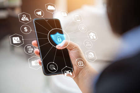 a woman's hand holding a smartphone along with graphics of protection from data theft