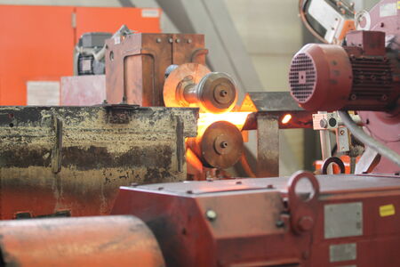 Moving the heated metal rod through the rollers in rolling mill