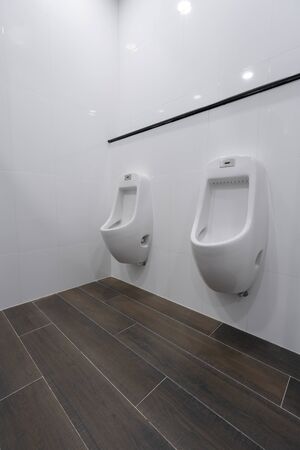 Row of white ceramic urinal chamber pot interior design with beautiful white wall men public toilet or restroom interior modern building decoration conceptの写真素材
