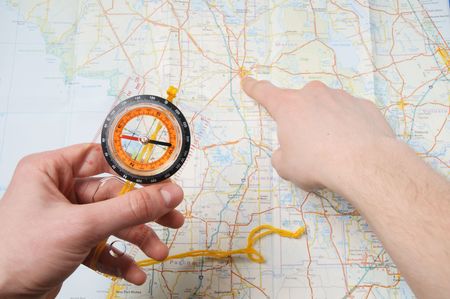 person hands holding compass and right hand show some point on city map
