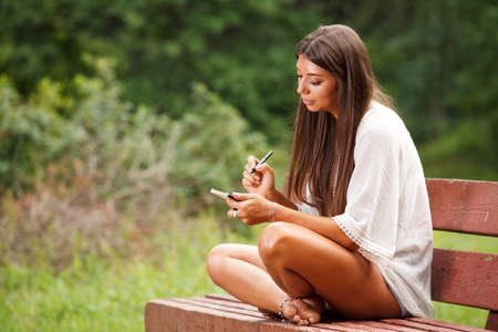 Beautiful woman writing in a small bookの写真素材