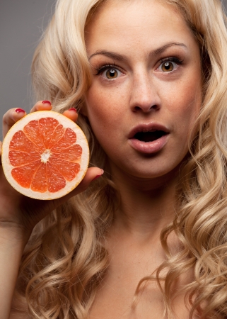 Smiling woman holding grapefruit in handの写真素材