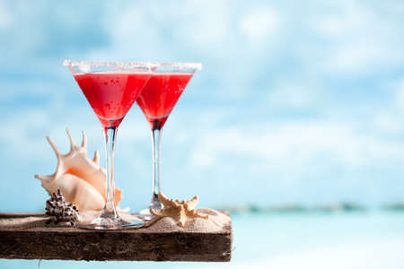 Tasty red drink on beach with ocean on sky backgroundの写真素材