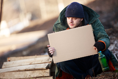 Homeless man holds blank cardboard for your textの写真素材