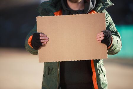 Homeless man holds blank cardboard for your own textの写真素材
