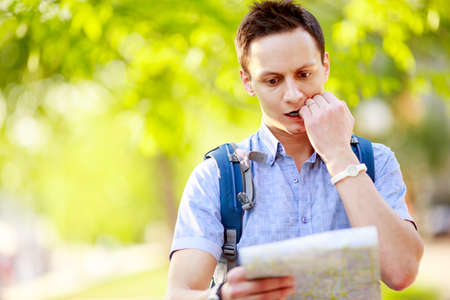 Young man with a map outdoorsの写真素材