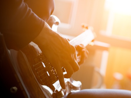 Male hand playing on acoustic guitar. Close-up.