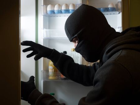 Thief. Man in black mask with a cake.