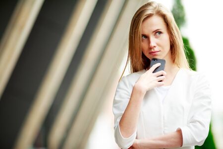 Beautiful casual woman with cell phone over defocused city backgroundの写真素材