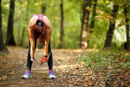 young fit woman doing exercise in park, rear view