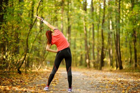 woman exercising in park, stretching hands upの写真素材