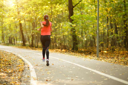 young fitness woman running at forest trail in park