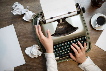 Vintage typewriter and blank sheet of paper, human hands