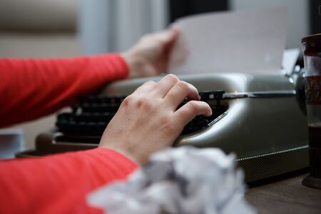 woman working on typewriter pulls paper out at tableの写真素材