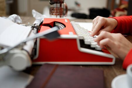 woman at table typing on old red typewriterの写真素材
