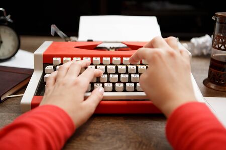 Vintage red typewriter with blank paper on wooden deskの写真素材