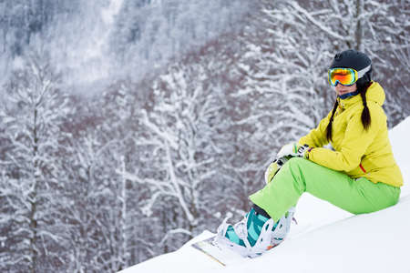 Portrait of snowboarder woman on background beautiful landscape of snowy mountains.の写真素材