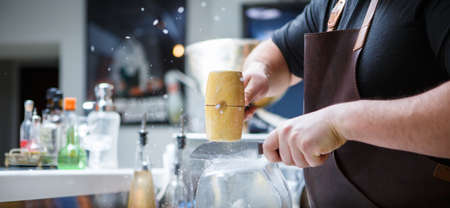 Bartender mannually crushed ice with wooden hammer and metal knife.の写真素材