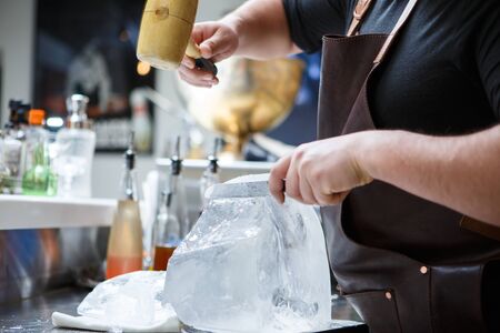 Bartender mannually crushed ice with wooden hammer and metal knife.の写真素材