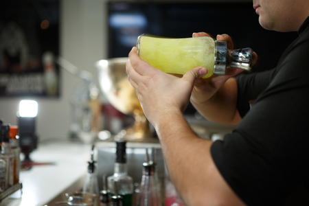 Bartender at work preparing cocktails. Shaking cocktail shaker.の写真素材