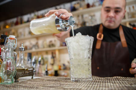 Bartender pouring cocktail into glass at the barの写真素材