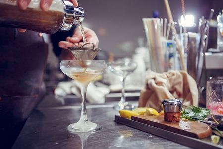 Bartender coocks cocktail behind a bar counter. Toned image.の写真素材
