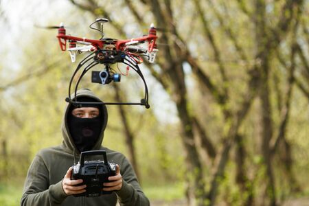 Man in mask operating a drone with remote control. Crime conceptの写真素材