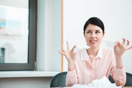 business woman sitting her desk getting rid of old papers with pleasure.の写真素材