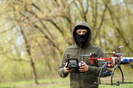 Man in mask flying with the drone. Technology thief concept