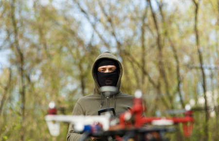 Man in mask flying with the drone. Technology thief concept