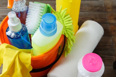 Plastic bucket with cleaning supplies on wood background. Focused on green brush.の写真素材