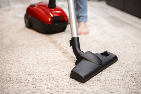 Maid cleaning carpet at home with modern vacuum cleanerの写真素材