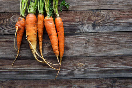 Raw carrot with green leaves on wooden backgroundの写真素材