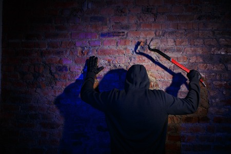 Gunman surrenders standing back against brick wallの写真素材