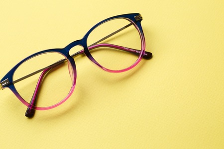 Blue-pink glasses with transparent lenses on yellow background emptyの写真素材