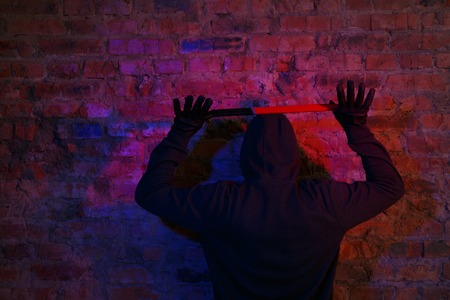 Thief with raised arms standing at the brick wall with by master keyの写真素材