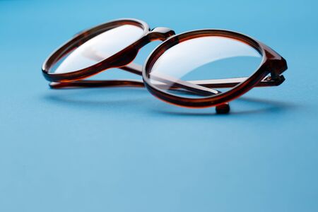 Folded brown spectacles close up on blue background emptyの写真素材