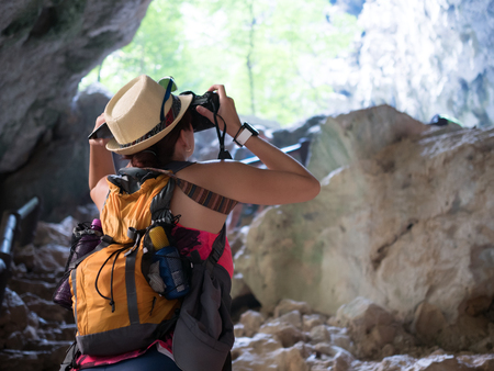 Brunette with camera among rocksの写真素材