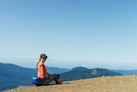 Photo of girl in sunglasses sitting on edge of hillの写真素材